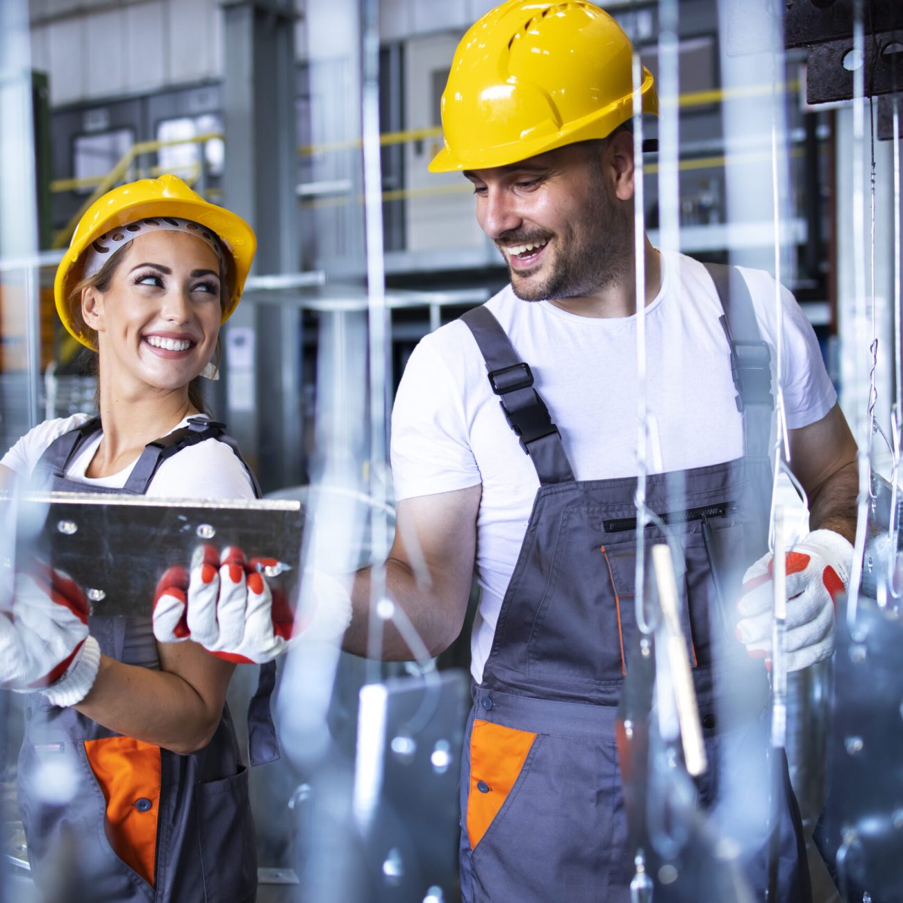 Factory workers working together in industrial metal production line.