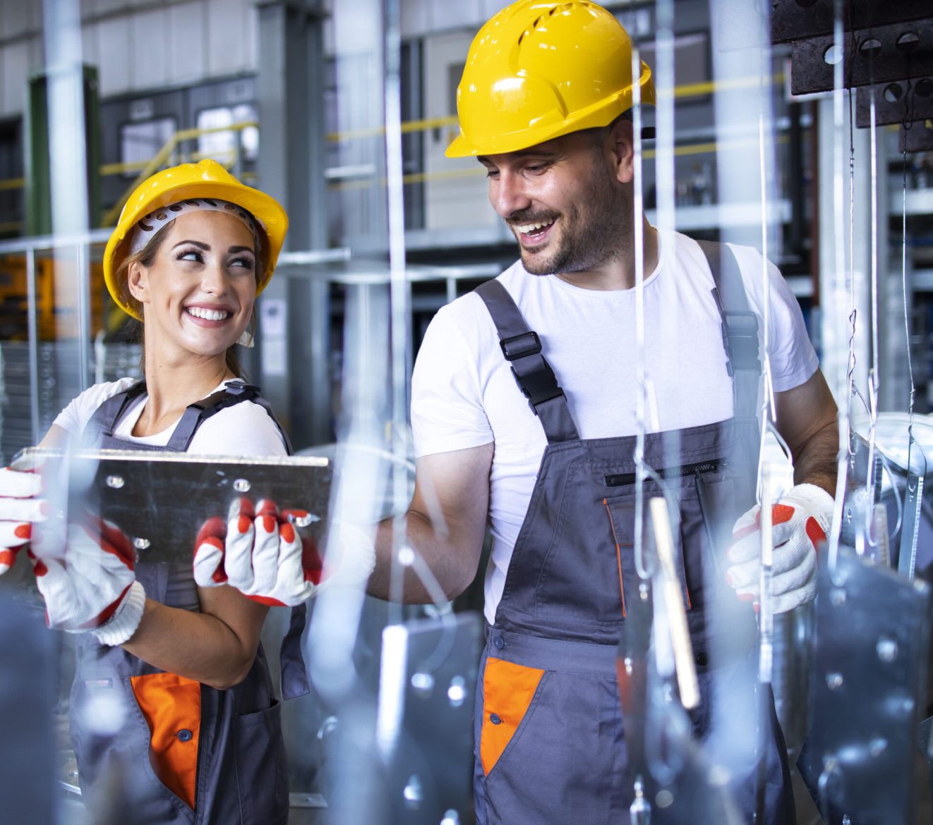 Factory workers working together in industrial metal production line.